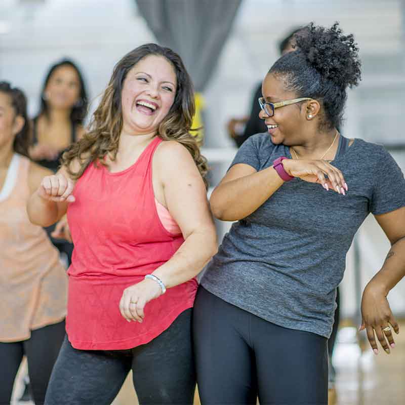 TheWebDoctor Two woman in an exercise class enjoying life with hearing aids.